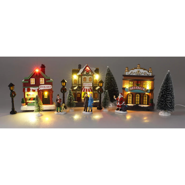 Lit village set with a bookshop, gift shop and theatre, lamp posts, snowy trees and figures including Santa