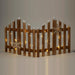 Rustic wooden picket fence with snow-tipped posts, wooden snowflakes and warm fairy lights