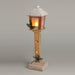 Wooden streetlamp with a snowy roof, glowing lantern and pine and berry sprigs