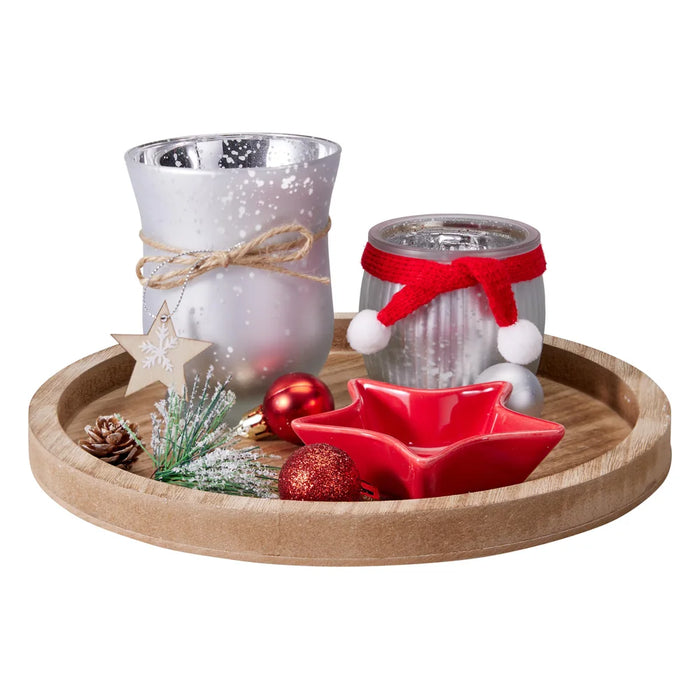 Round wooden tray with two frosted silver glass tealight holders, a red star dish, pine cone, snowy sprig and baubles