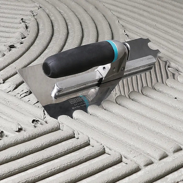 Bihui Jumbo 8 Piece Trowel Set displayed on a workbench with adhesive and tiles, showing full range of trowels and notches.