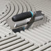 Bihui Jumbo 8 Piece Trowel Set displayed on a workbench with adhesive and tiles, showing full range of trowels and notches.