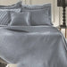 Denim Margot bedspread styled on a bed, showing deep denim blue quilted finish in a stylish room setting.