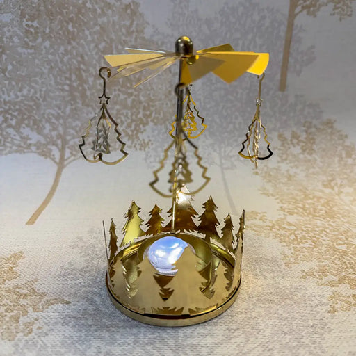 Close-up of gold carousel tealight holder featuring small Christmas tree cutouts spinning in candlelight.