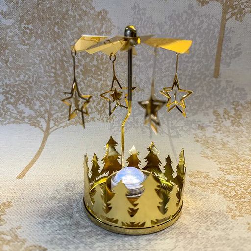 Close-up of gold star carousel tealight holder with fine star cutouts spinning in warm candlelight.