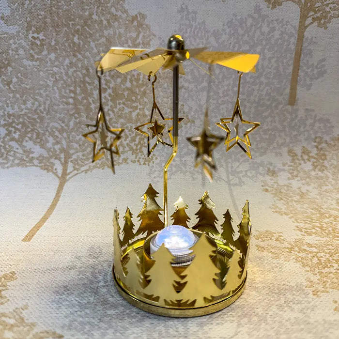 Close-up of gold star carousel tealight holder with fine star cutouts spinning in warm candlelight.