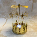 Close-up of gold star carousel tealight holder with fine star cutouts spinning in warm candlelight.