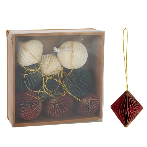 Close-up of red, green, and white paper baubles showing folded paper texture and soft matte finish.