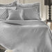 Light Grey Margot bedspread styled on a bed in a contemporary bedroom, showing quilted fabric in a neutral shade.