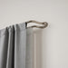 Midnight matt nickel double wrap-around curtain pole fitted with two layers of curtains for reduced light leakage
