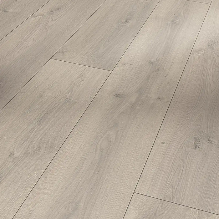 Close-up of Oak Mistral Grey laminate plank, revealing subtle wood knots and flowing grain patterns in a soft grey finish with a natural texture.