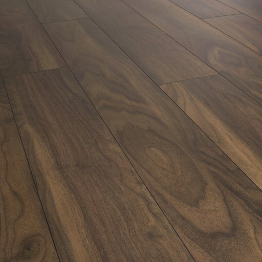 Close-up of Noce Rubio Solid 12mm laminate flooring showing warm walnut tones and realistic woodgrain texture.
