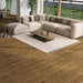 Laminate flooring in Orion Beam displayed in a modern, open-plan living room with soft lighting and minimalist furniture, highlighting the warm oak tones and narrow plank design.