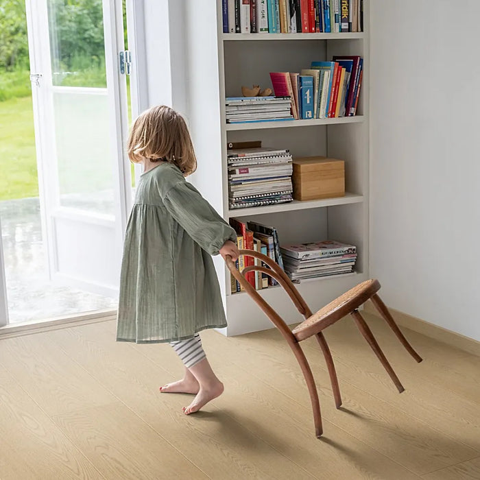 Living room with Pergo Odense Malt laminate flooring in warm caramel tones, styled with natural light and cozy neutral decor.