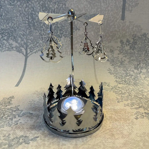 Close-up of silver carousel tealight holder with tiny Christmas tree shapes reflecting light.