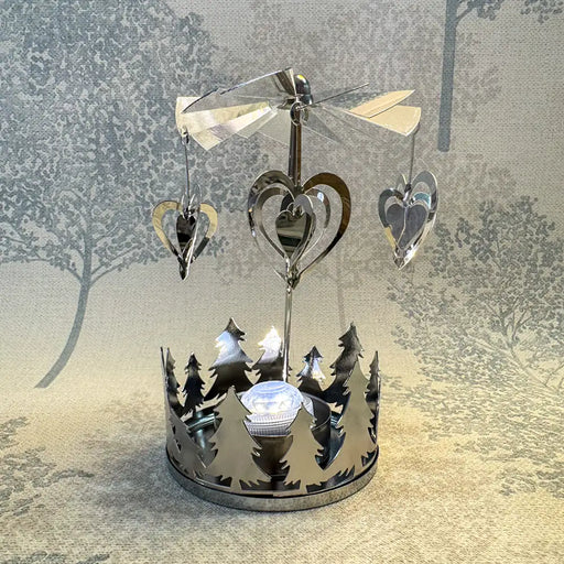 Close-up of silver heart carousel tealight holder showing heart details spinning under candlelight.