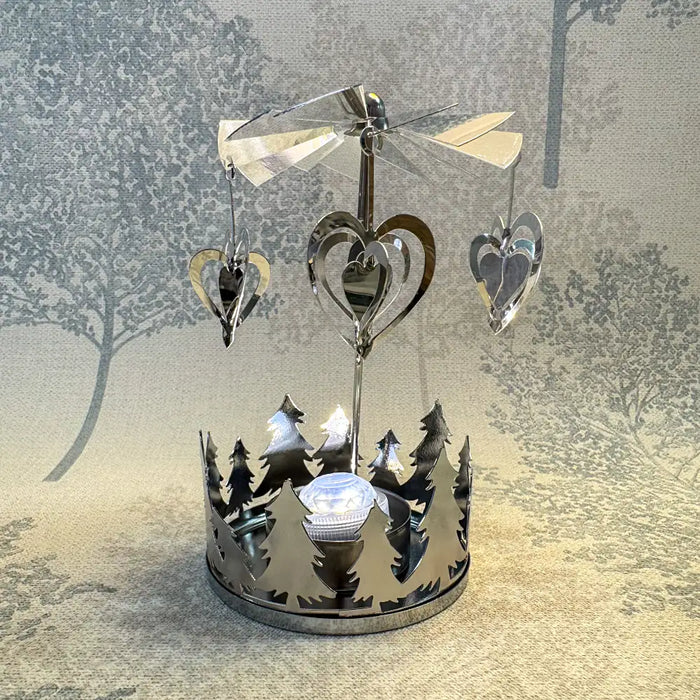 Close-up of silver heart carousel tealight holder showing heart details spinning under candlelight.
