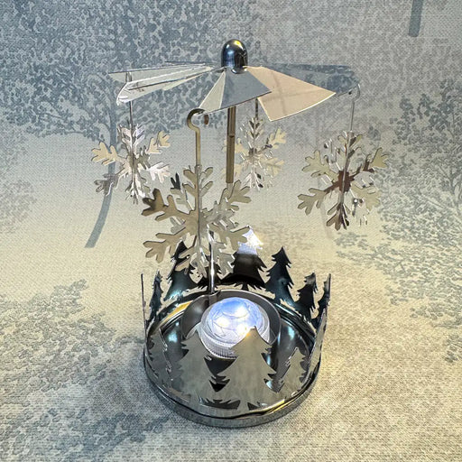 Close-up of silver snowflake carousel tealight holder showing reflective snowflake patterns.
