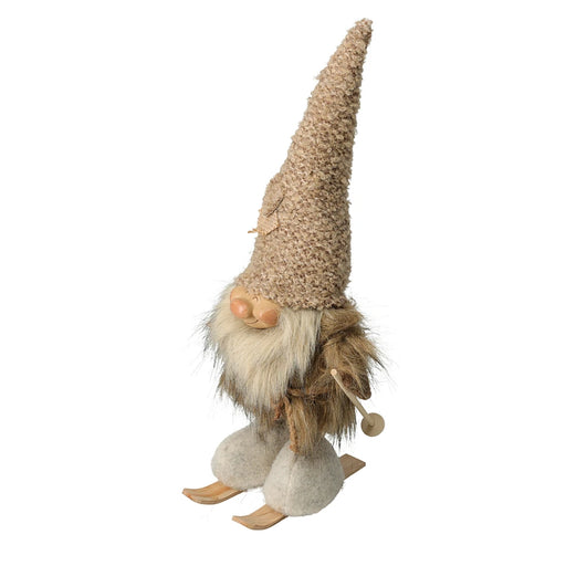 Close-up of skiing gnome man figurine wearing winter clothes and holding skis.