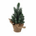 Close-up of snowy Christmas tree branches in a burlap pot showing white frosted tips and natural jute texture.