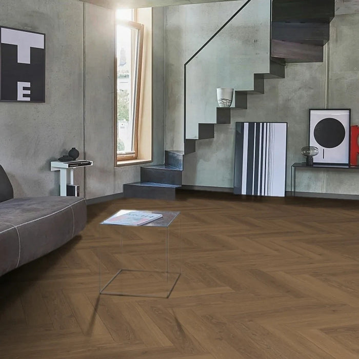 Studioline Honey Herringbone laminate flooring styled in a traditional pattern, showcasing warm oak tones and a realistic wood grain finish in a light-filled room.