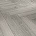 Close-up of Studioline Light Grey Herringbone laminate showing the natural matt finish, fine woodgrain detail, and bevelled plank edges.