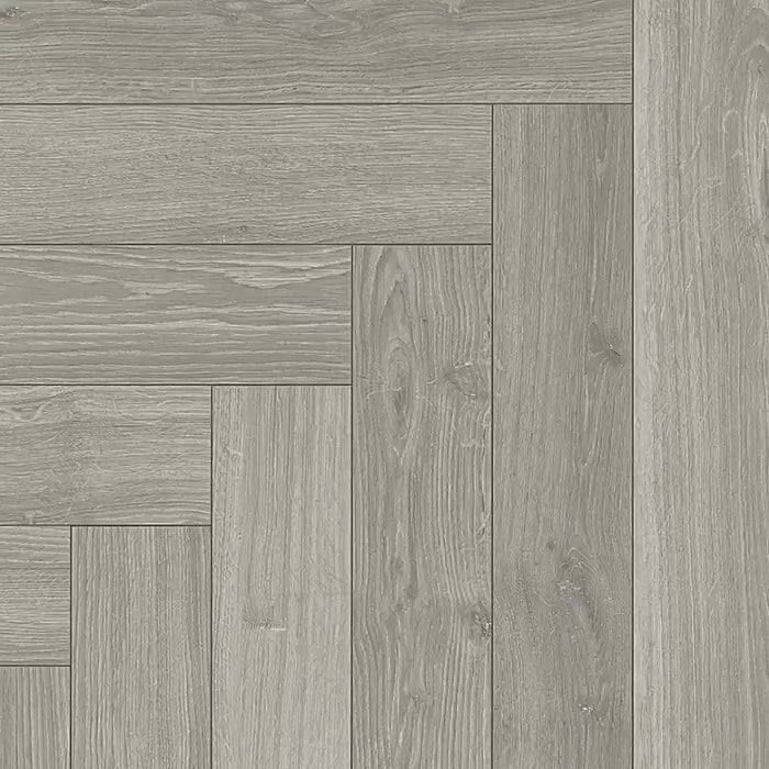 Close-up of Studioline Light Grey Herringbone laminate showing the natural matt finish, fine woodgrain detail, and bevelled plank edges.