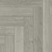 Close-up of Studioline Light Grey Herringbone laminate showing the natural matt finish, fine woodgrain detail, and bevelled plank edges.