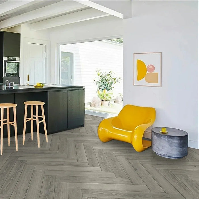 Light grey oak herringbone laminate flooring in a bright modern living space, highlighting its soft neutral tones and clean parquet layout.