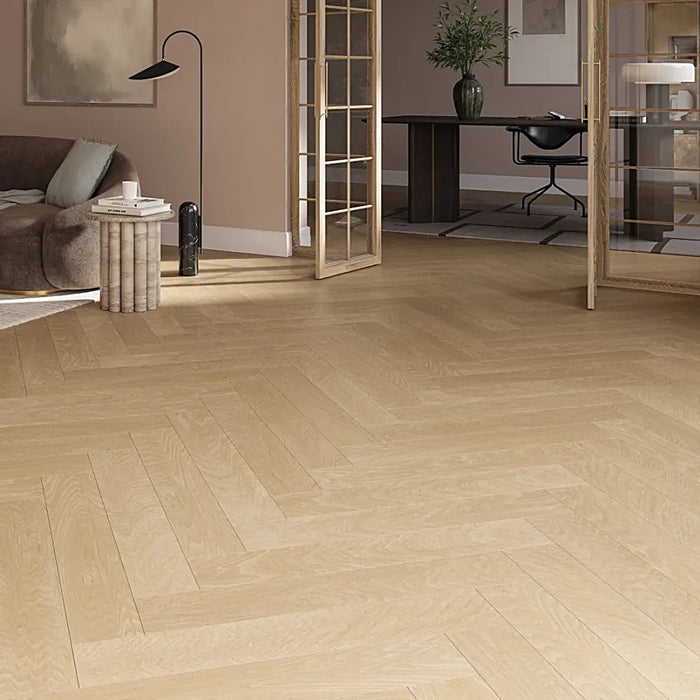 Natural oak herringbone laminate flooring styled in a warm, elegant living room, highlighting its realistic parquet look and golden-brown tones.