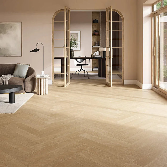 Natural oak herringbone laminate flooring styled in a warm, elegant living room, highlighting its realistic parquet look and golden-brown tones.
