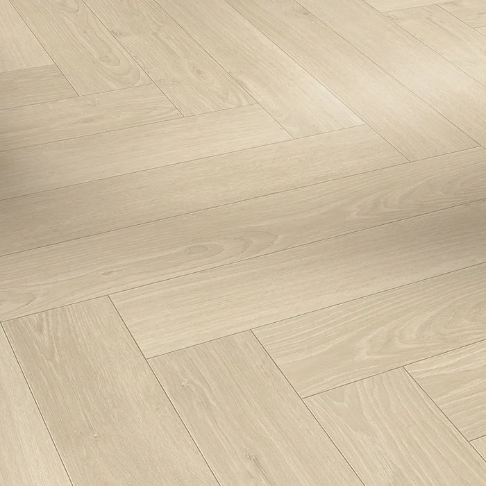 Detail of the Studioline Sanded Herringbone laminate showing the textured, natural matt finish and refined oak grain pattern.