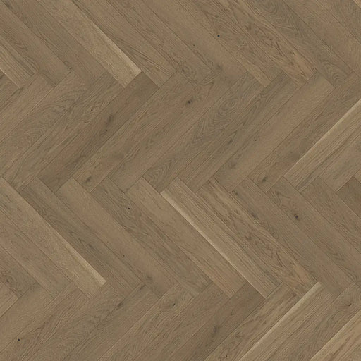 Close-up of Trendtime 3 Nougat Herringbone flooring showing the warm oak tones, fine grain detail, and precisely beveled edges.