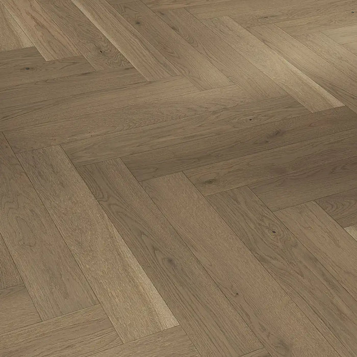 Close-up of Trendtime 3 Nougat Herringbone flooring showing the warm oak tones, fine grain detail, and precisely beveled edges.