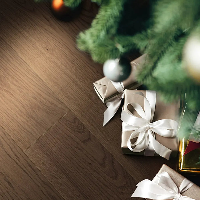 Wide plank Trendtime 4 Living Nougat engineered wood flooring in a modern, softly lit living room with natural textures and warm tones.