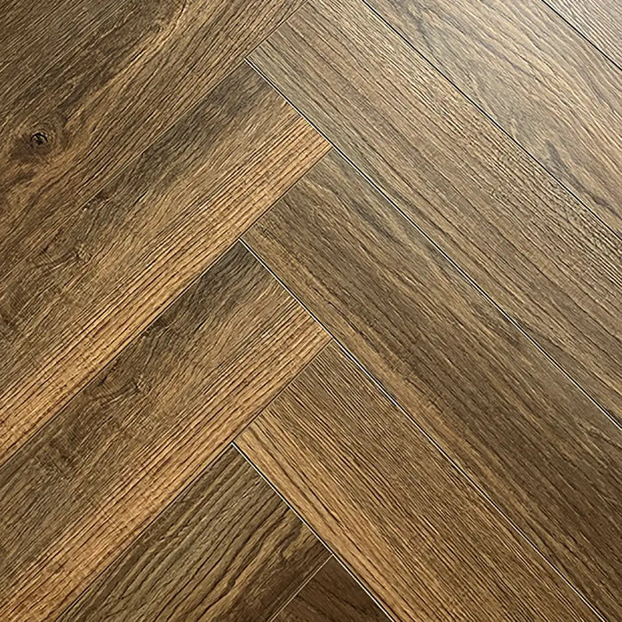 Close-up of Tudor Oak 12mm Herringbone laminate flooring showing rich oak tones and detailed woodgrain texture.