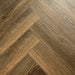 Close-up of Tudor Oak 12mm Herringbone laminate flooring showing rich oak tones and detailed woodgrain texture.
