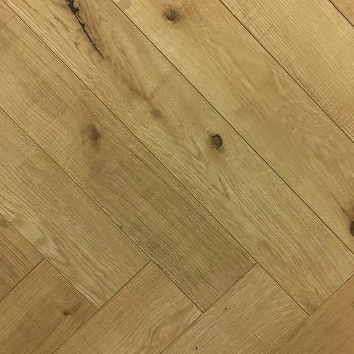 Close-up of Winchester Oak 12mm herringbone laminate flooring, showing the detailed wood grain and rich oak tones.