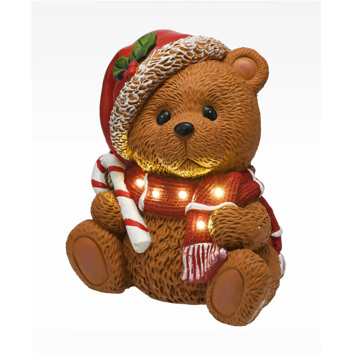 Sitting Christmas bear in a Santa hat and red scarf holding a candy cane, lit with warm LEDs