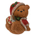 Sitting Christmas bear in a Santa hat playing a red and gold drum