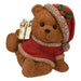 Sitting Christmas bear in a Santa hat and red jumper holding a gold wrapped gift