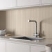 Earth Sand porcelain tiles installed vertically as a contemporary kitchen splashback with white cabinetry and a quartz worktop.