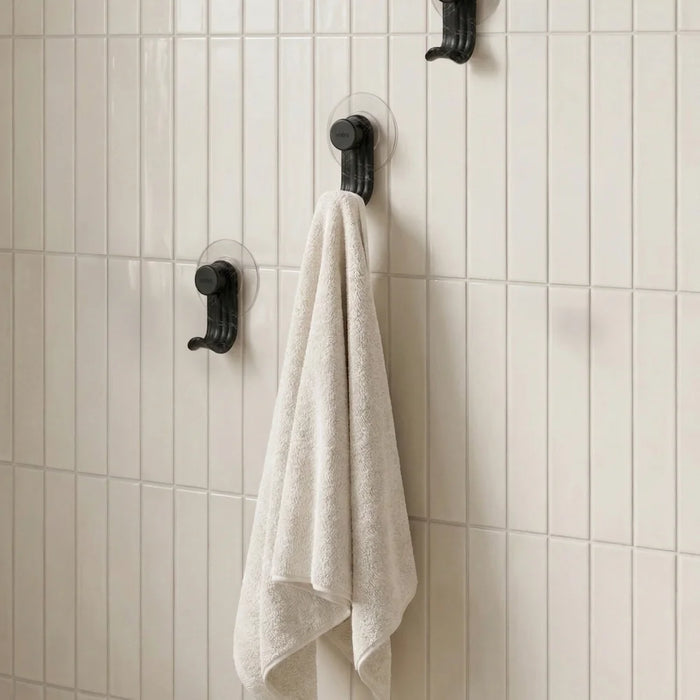 Nami adhesive hooks in black colour on white tile wall with towel