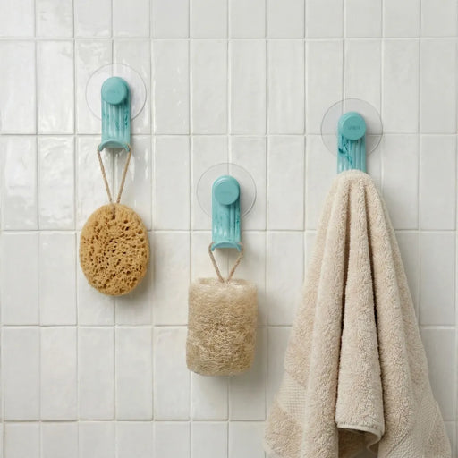Nami adhesive hooks in ocean blue colour on white tile with sponge, loofah and towel