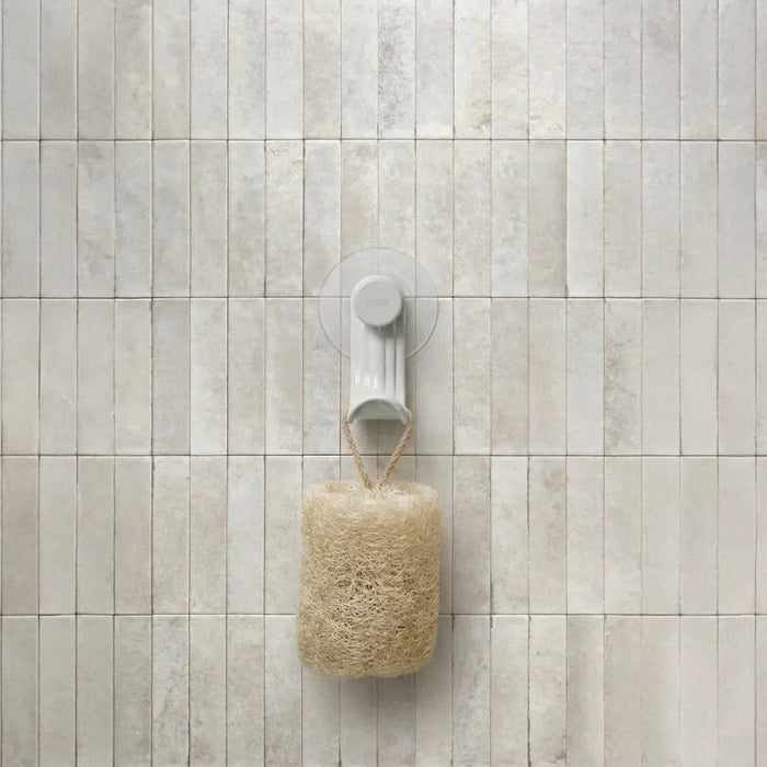 Nami adhesive hook in sand colour on tile wall holding a loofah