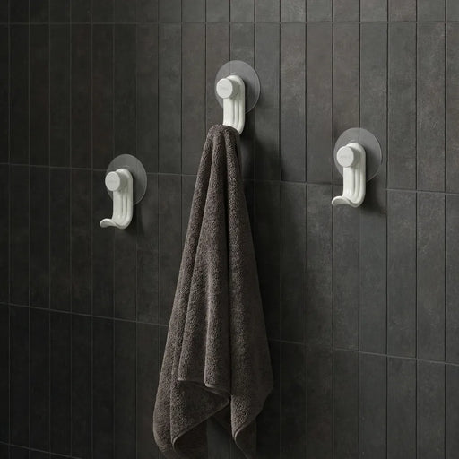 Nami adhesive hooks in sand colour on dark tile wall with towel