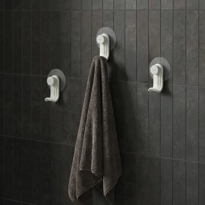 Nami adhesive hooks in sand colour on dark tile wall with towel