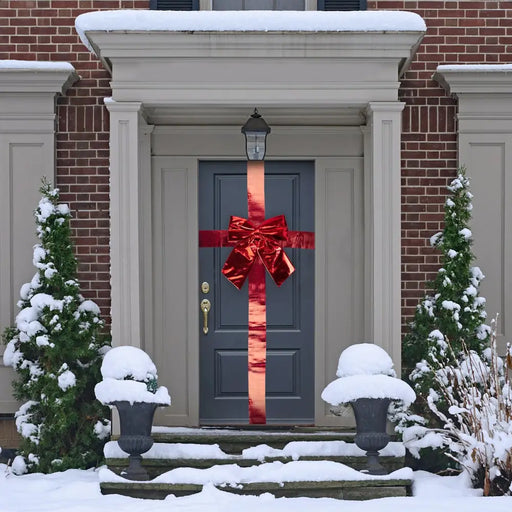 Front door dressed like a present with a shiny red bow and ribbon, in a snowy porch setting