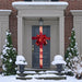 Front door dressed like a present with a shiny red bow and ribbon, in a snowy porch setting