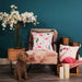 A living room setting with a chair and Ci FiFi flamingo printed design cushion on faux linen with multicoloured pom pom